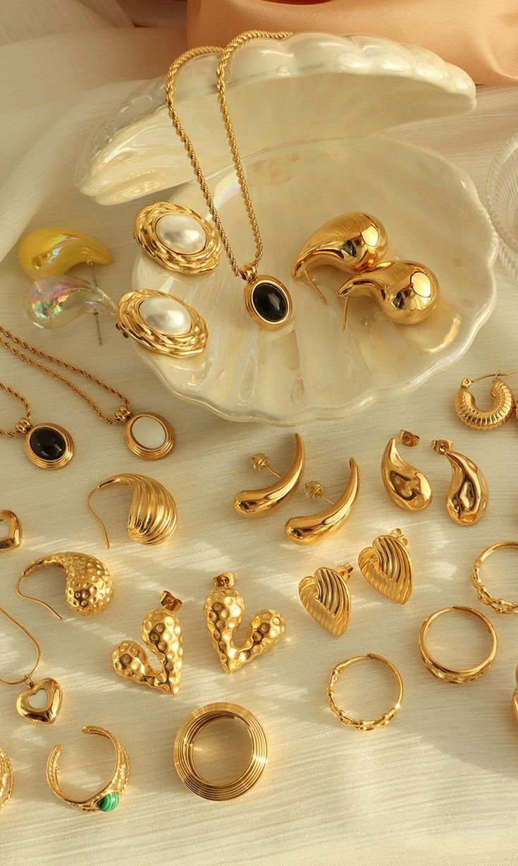 Gold earrings, pendants and rings arranged in a pearl shell dish
