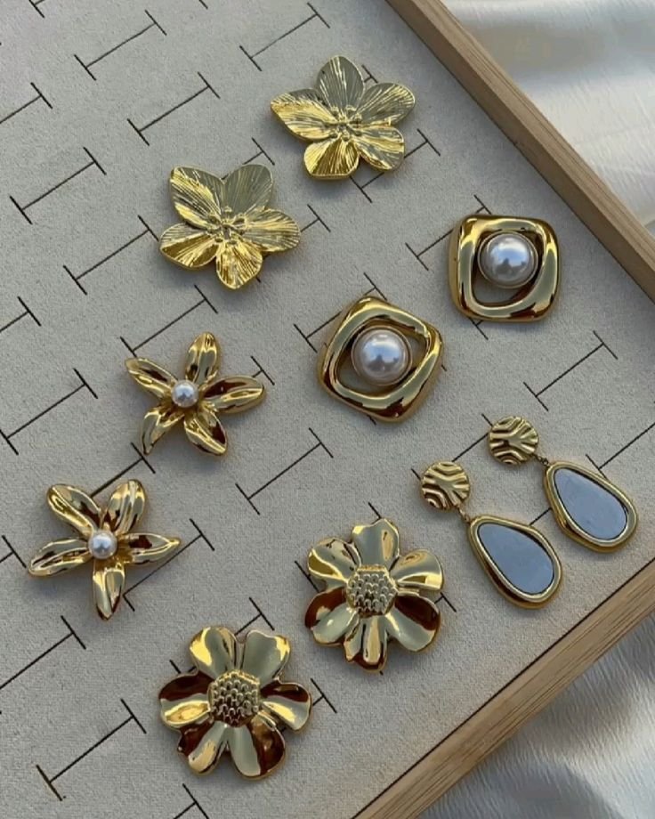 Gold flower and pearl earrings set on a velvet display tray
