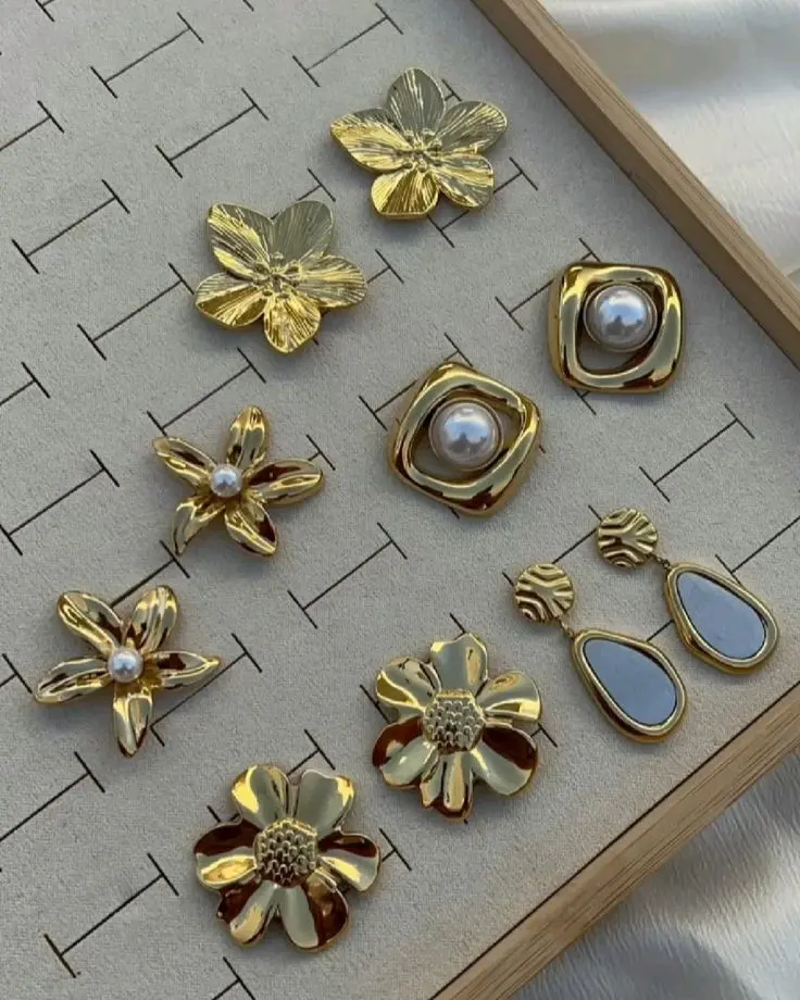Gold flower and pearl earrings set on a velvet display tray