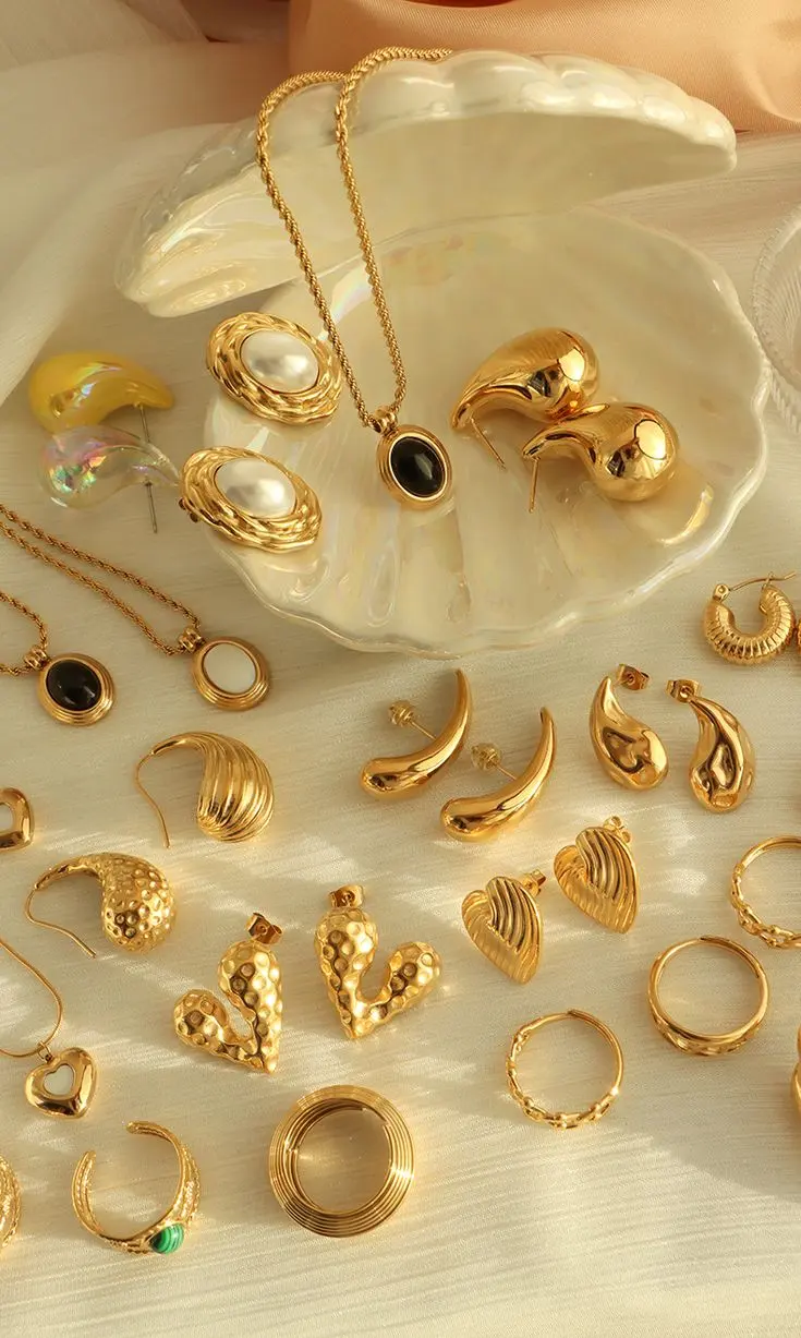 Gold earrings, pendants and rings arranged in a pearl shell dish